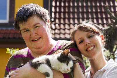 woman is holding a cat with caregiver