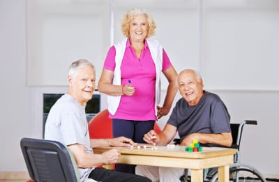 Three happy senior citizens playing Bingo together in a nursing home