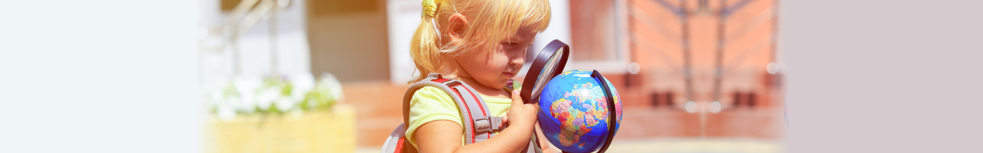 beautiful little girl holding a magnifying glass and a globe